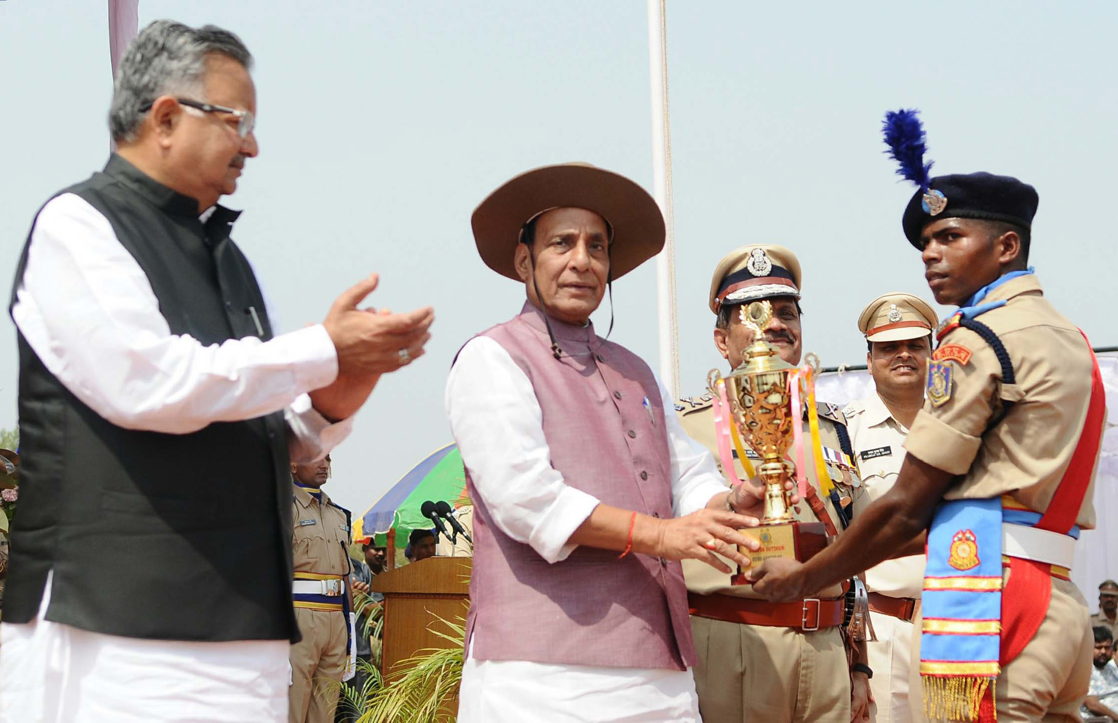 The Union Home Minister, Shri Rajnath Singh presenting the trophies, on the occasion of the Passing Out Parade of the Bastariya Battalion of CRPF, at Ambikapur, in Chhattisgarh on May 21, 2018.  	The Chief Minister of Chhattisgarh, Dr. Raman Singh is also seen.